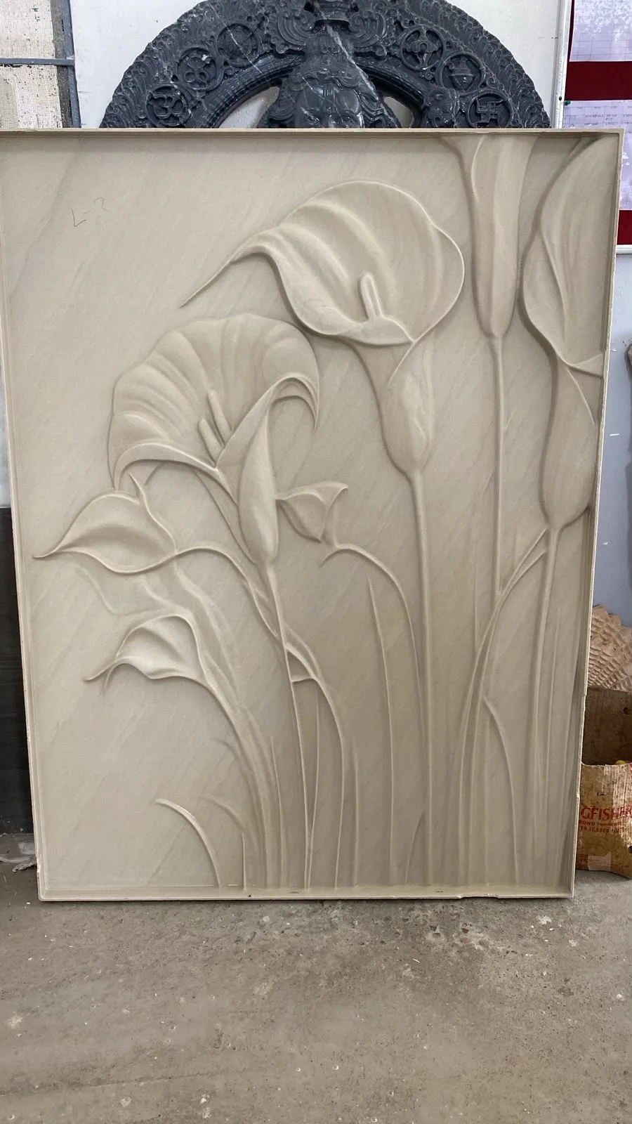 Carved stone floral relief panel in a workshop